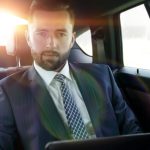 businessman with laptop sitting in a comfortable car